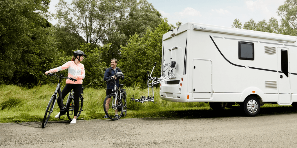 Thule Lift, sähköinen pyöräteline, vieressä kaksi henkilöä polkupyörien kanssa